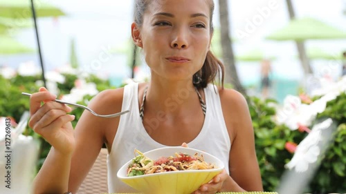 Woman eating salad at restaurant outdoors in summer. 59.94 FPS. photo
