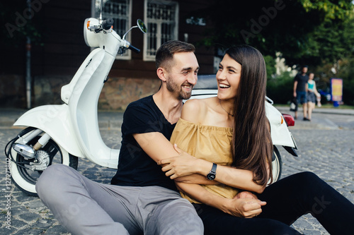 Cute couple with their scooter in the city