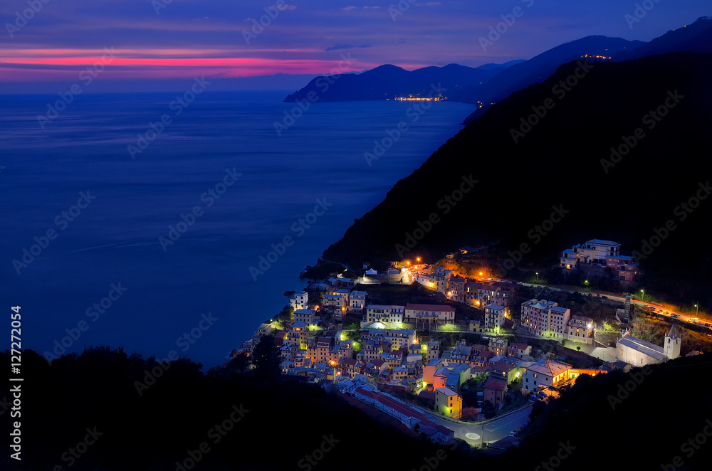 Manarola top view at down. Night view with city lights. Cinque Terre coast and sea after sunset.