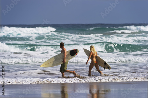 Two Surfers walk into the Ocean. photo