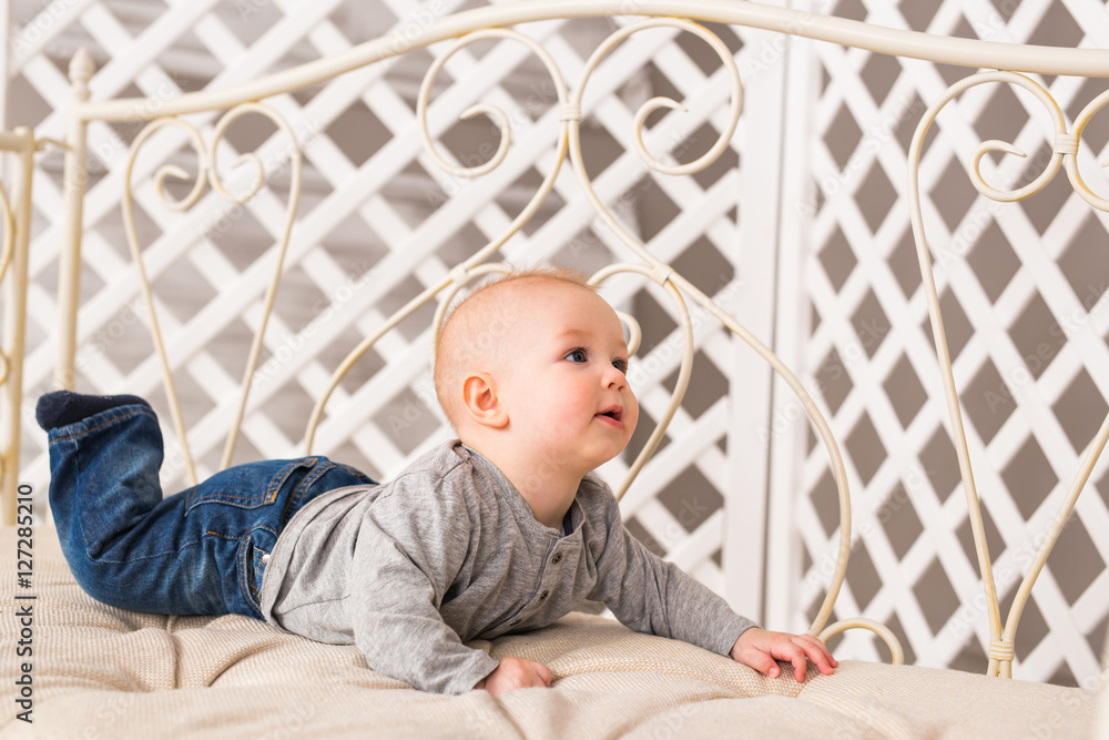 Naklejka premium Adorable baby boy in white sunny bedroom. Newborn child relaxing. Family morning at home.
