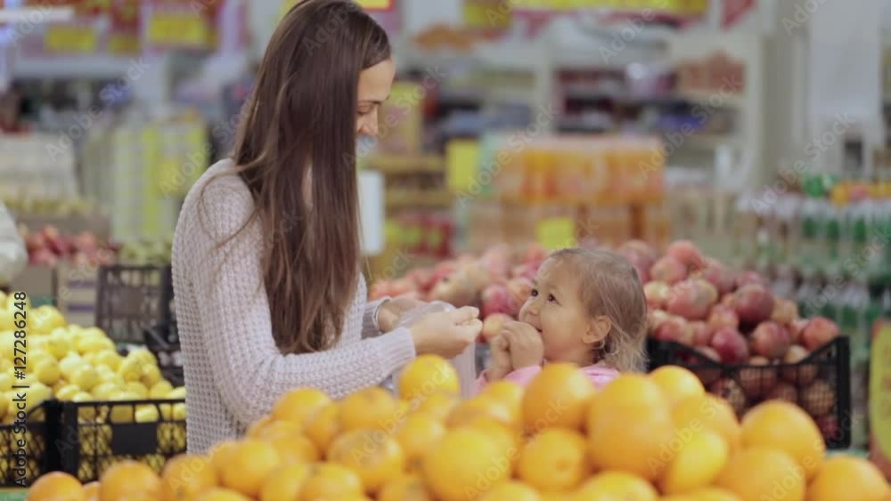 Mother and baby daughter in supermarket buying fruits and vegetables Mother and baby daughter in supermarket buying fruits and vegetables