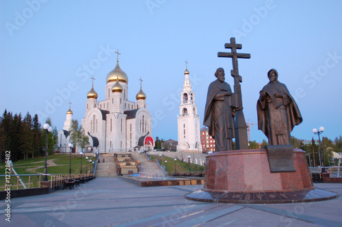 11 июня 2013 года Россия, ХМАО ЮГРА, город Ханты-Мансийск, памятник основателям славянской письменности Кириллу и Мефодию, Аллея Славянской письменности, храм воскресения господня и колокольня photo