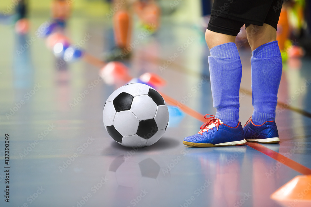Children training soccer futsal indoor gym. Young boy with soccer ball training indoor football. Little player in dark blue sports socks