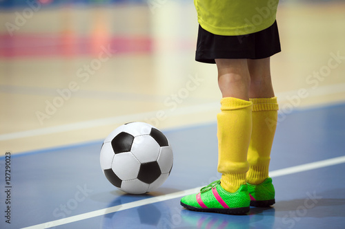 Football futsal training for children. Indoor soccer young player with a soccer ball in a sports hall. Player in yellow uniform. Sport background.