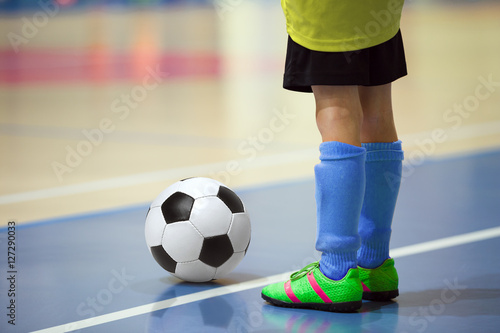 Football futsal training for children. Indoor soccer young player with a soccer ball in a sports hall. Player in yellow and blue uniform. Sport background.