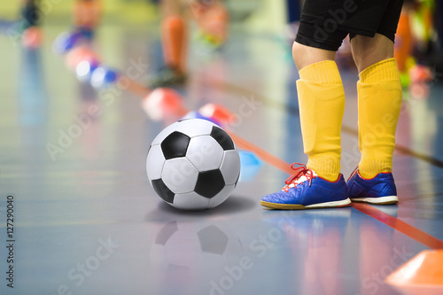 Children training soccer futsal indoor gym. Young boy with soccer ball training indoor football. Little player in yellow sports socks