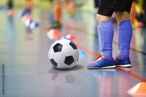 Children training soccer futsal indoor gym. Young boy with soccer ball training indoor football. Little player in dark blue sports socks