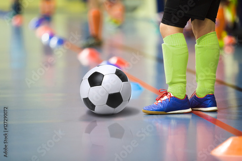 Children training soccer futsal indoor gym. Young boy with soccer ball training indoor football. Little player in light green sports socks