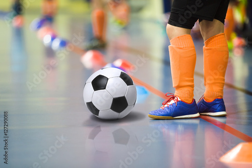Children training soccer futsal indoor gym. Young boy with soccer ball training indoor football. Little player in light orange sports socks