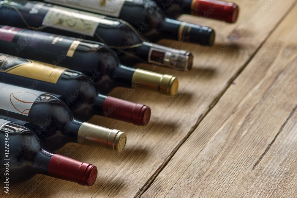 Row of red dry wine bottles on wooden background. Low depth of field. Row of red dry wine bottles on wooden background. Low depth of field.