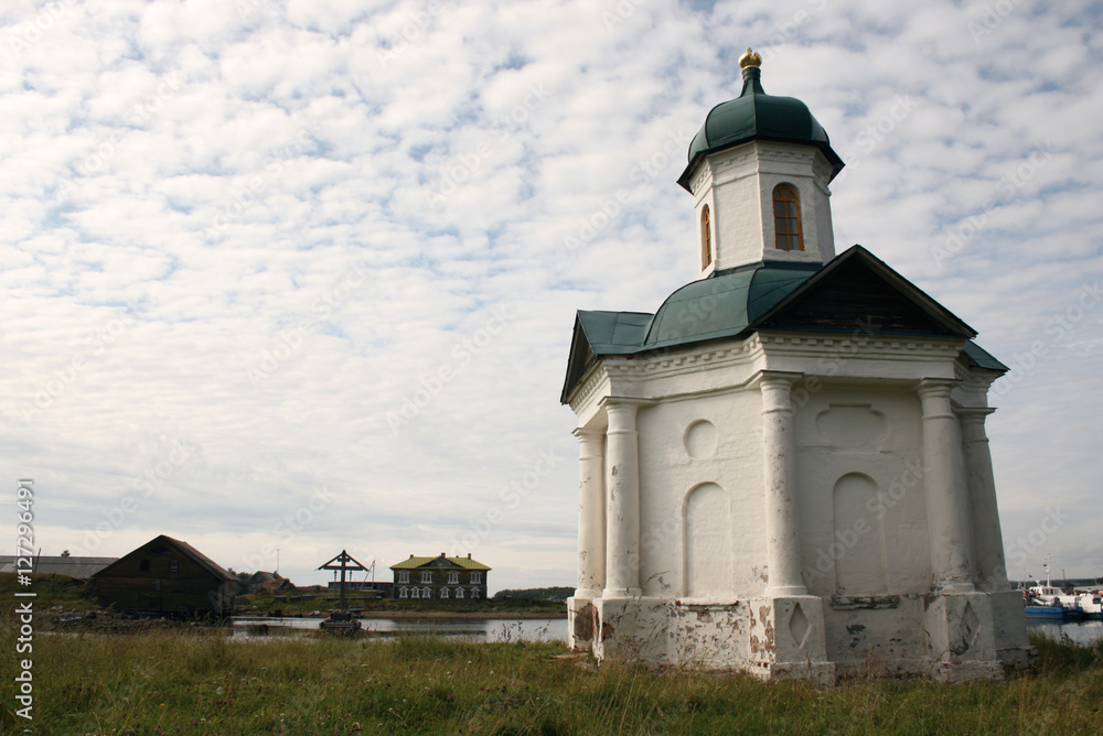 Alexander chapel on the shore of the bay of Wellbeing and Memorial cross at Solovki islands in White sea, Russia