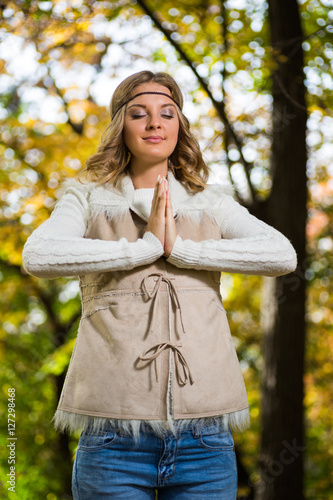 Beautiful boho girl enjoys meditating in the park.