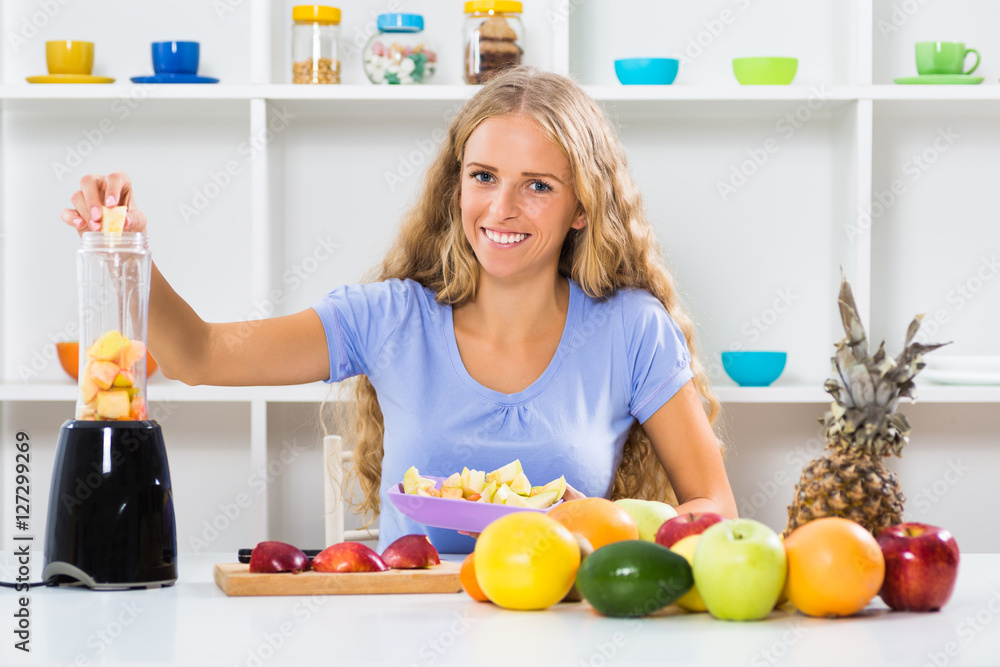 Beautiful girl enjoys making smoothie at her home.

