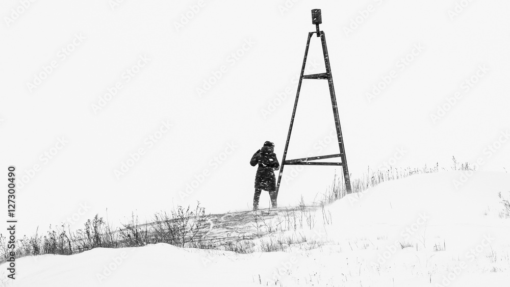 Geodesic triangulation mark. Men on the street in winter. Strong storm, blizzard, cold. Defocused nature. Black and white photo of an extreme, snowy, windy winter. In high-key. Atmospheric photos.