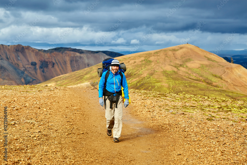 man hiker on the trail in the rhyolite Islandic mountains. Trek in National Park Landmannalaugar, Iceland