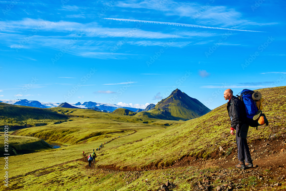 man hiker on the trail in the Islandic mountains. Trek in National Park Landmannalaugar, Iceland. valley is covered with bright green moss