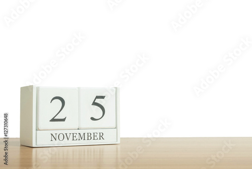 Closeup surface white wooden calendar with black 25 november word on blurred brown wood desk isolated on white background with copy space , selective focus at the calendar