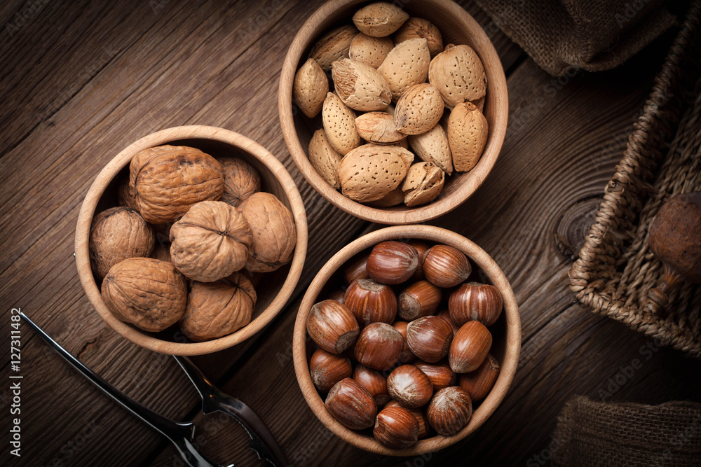 Walnuts, hazelnuts and almonds in-shell in wooden bowl. Walnuts, hazelnuts and almonds in-shell in wooden bowl.