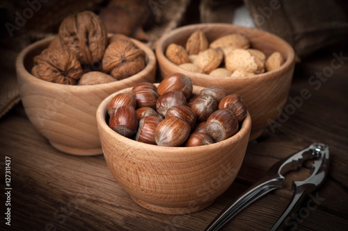 Walnuts, hazelnuts and almonds in-shell in wooden bowl.