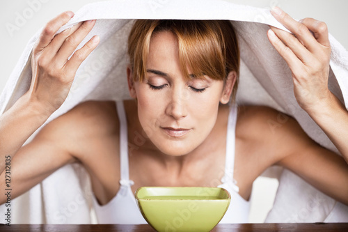 femme qui respire au dessus d'un bol chaud sous une serviette pour dégager son nez et ses bronches photo