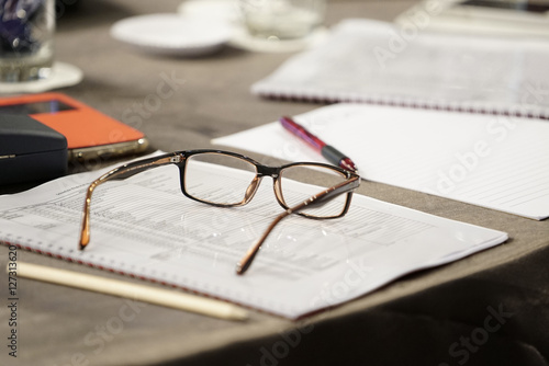 close up eyeglasses on table with pen in meeting room