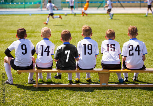 Football Players on Match Game. Young Soccer Team Sitting on Wooden Bench. Soccer Match For Children. Little Boys Playing Tournament Soccer Match. Youth Soccer Club Footballers photo