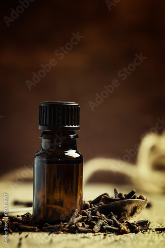 Essential oil of cloves in a brown bottle on a vintage wooden ba