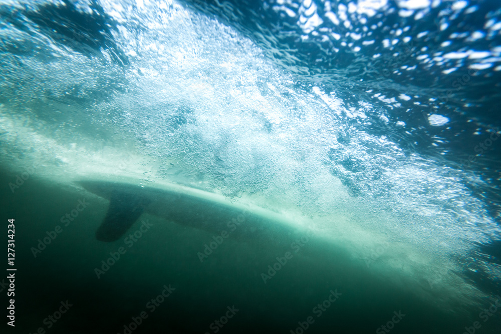 Obraz premium surfboard underwater with fin and air bubbles