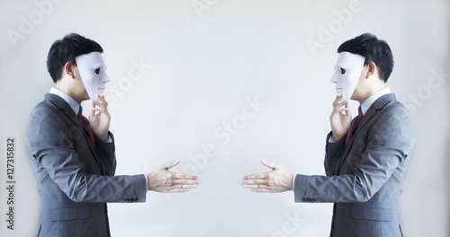 Fotografering Two men in business suit handshaking with masks on - Business fraud and hypocrit