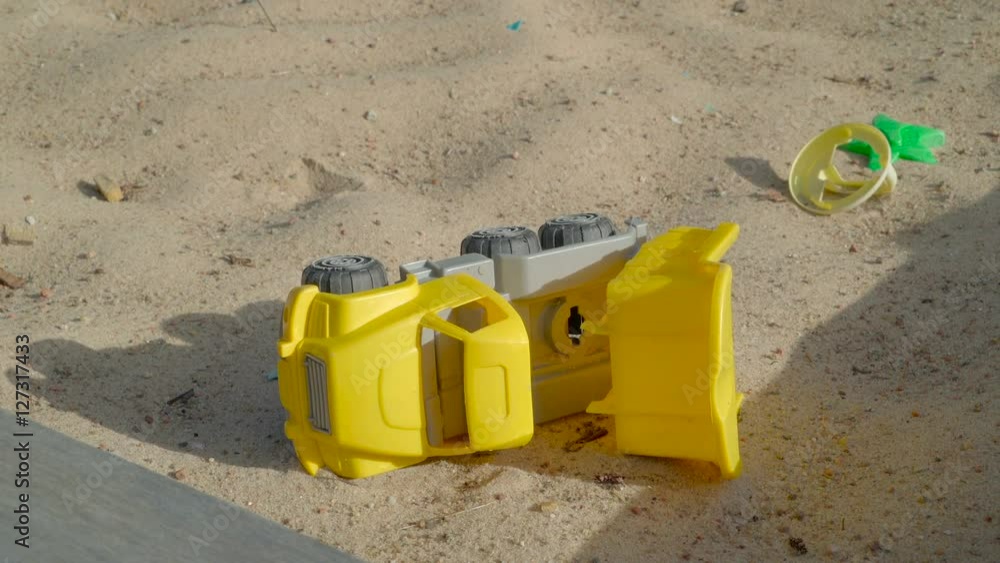 The yellow dumptruck toy on the white sand on sunny day along with the small toys beside the car in Ireland The yellow dumptruck toy on the white sand on sunny day along with the small toys beside the car in Ireland
