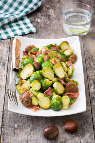Brussels sprouts with chestnuts and bacon on wooden table 