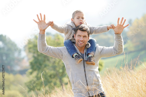 Daddy holding son on his shoulders out in the countryside