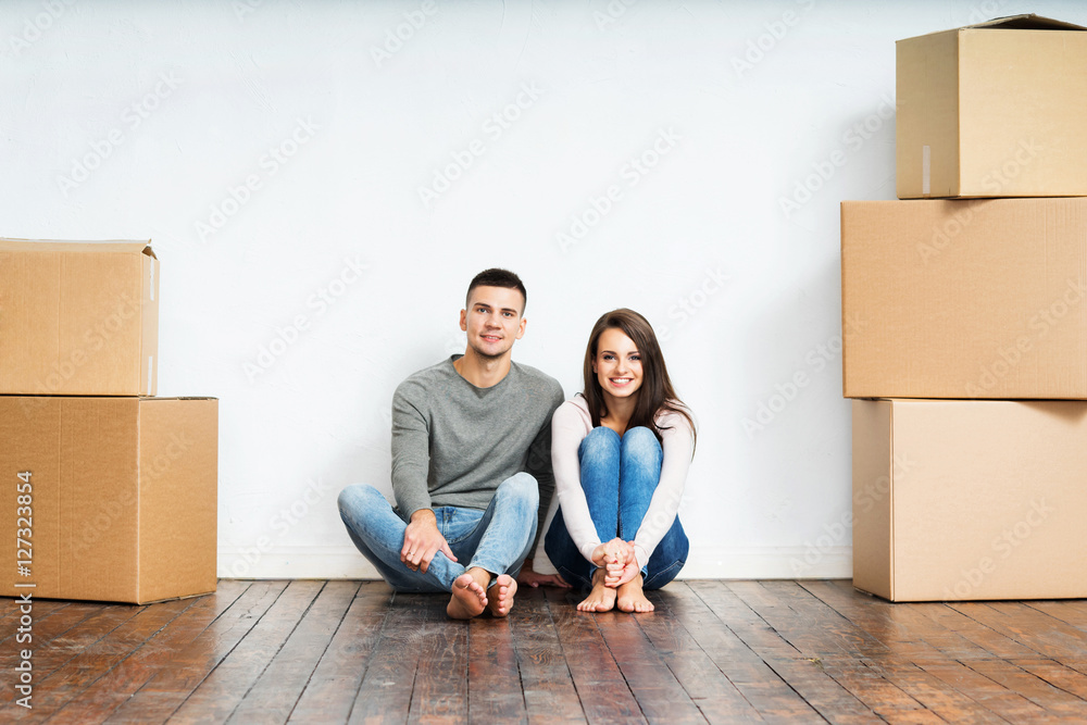 Couple sitting on the floor next to cardboard boxes Couple sitting on the floor next to cardboard boxes