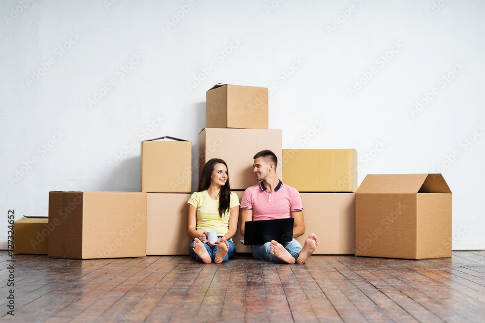 Young couple on the floor next to cardboard boxes Young couple on the floor next to cardboard boxes
