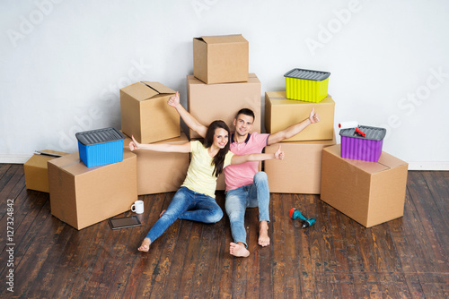Young couple on the floor next to cardboard boxes © Acronym