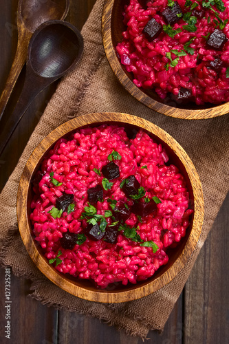 Beetroot risotto prepared with beetroot puree, roasted beetroot pieces and parsley on the top, photographed overhead with natural light (Selective Focus, Focus on the top of the risotto)