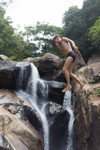 a man jumping off a cliff into the water