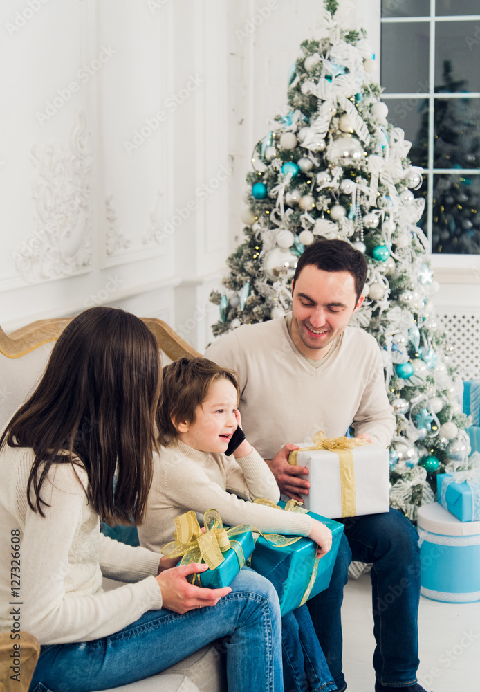 happiness, generation, holidays and people concept - happy family with gift boxes sitting on couch at home