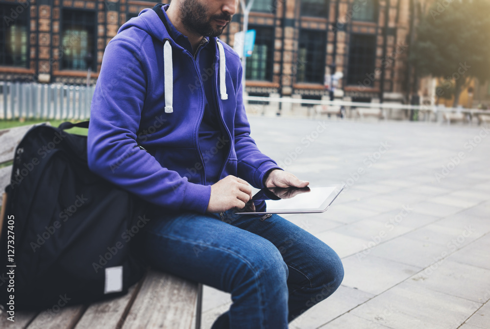 Hipster texting message on tablet computer or technology blank screen mockup. man with backpack using digital on red building castle background. Male hands tourist holding gadget on city landscape