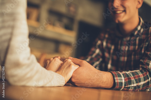 Couple in love holding hands in a cafe. Focus on hands.