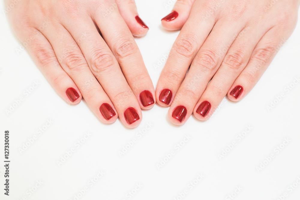 Close up of caucasian female hands with professional red manicure with glittering sparkles isolated on white background. Modern festive gel polish with base coat first and top cure with UV or LED lamp Close up of caucasian female hands with professional red manicure with glittering sparkles isolated on white background. Modern festive gel polish with base coat first and top cure with UV or LED lamp