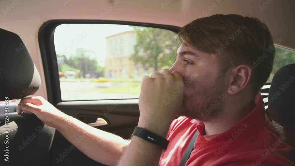 Young bearded man sitting inside driving car on back seat. Touching hair. Summer sunny day. Traveling. Young bearded man sitting inside driving car on back seat. Touching hair. Summer sunny day. Traveling.