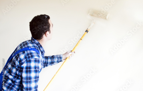 Worker house painter paints a wall