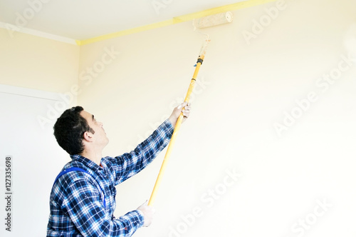 Worker house painter paints a wall
