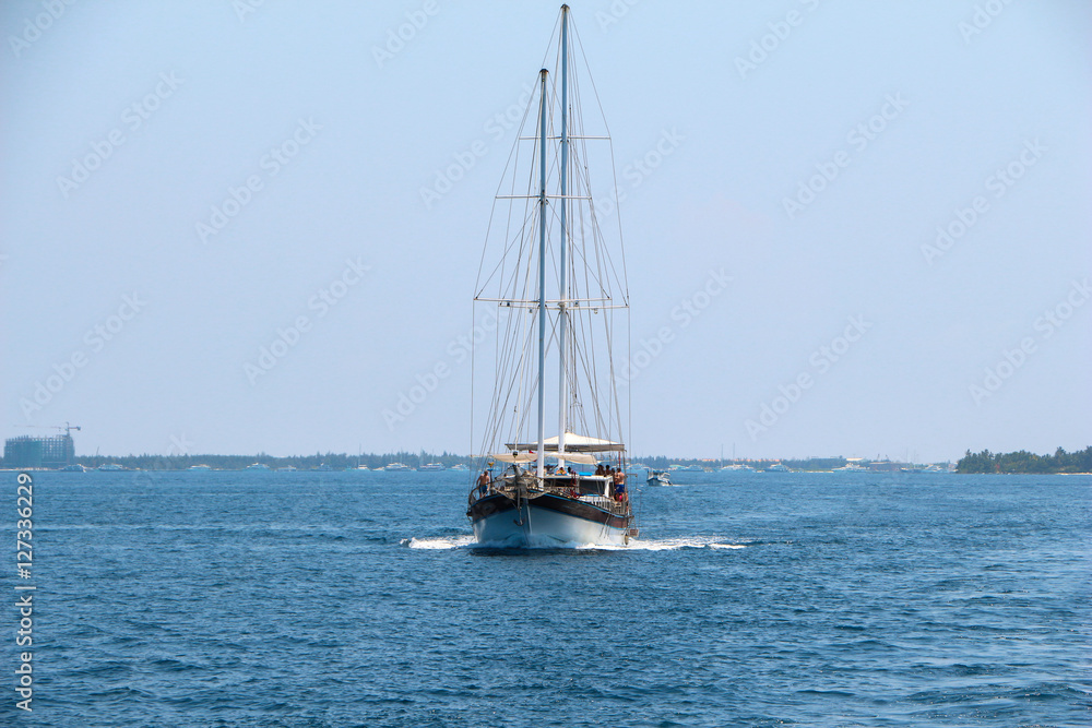 Nautical landscape with retro sailboat. Sea voyage on sailing yacht - luxury lifestyle in summer. Seashore near islands, soft light effect.