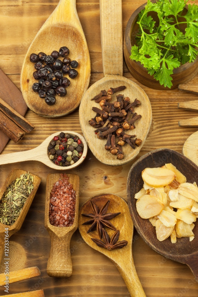 Various kinds of spices on the kitchen table. Seasoning food. Sales of exotic spices. Advertising on spices. Powder spices on spoons in wooden table background.
