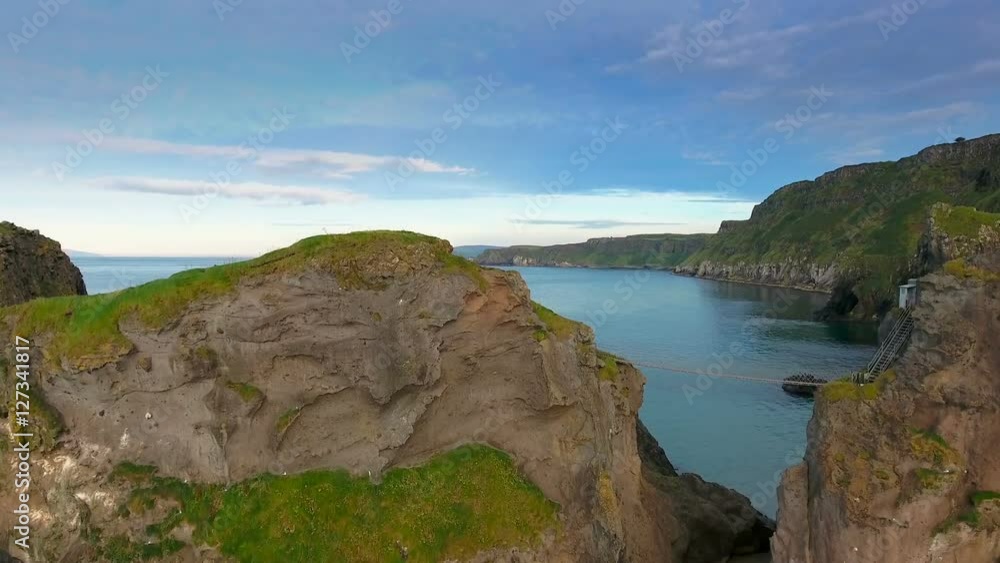 The amazing landscape view of the Carrick-a-Rede Rope Bridge and the big blue ocean on the islands in Ireland The amazing landscape view of the Carrick-a-Rede Rope Bridge and the big blue ocean on the islands in Ireland