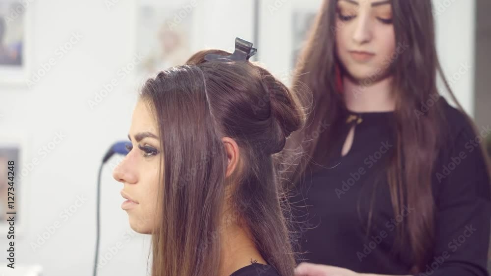 Attractive young woman having her hair styled by a hairdresser. Attractive young woman having her hair styled by a hairdresser.