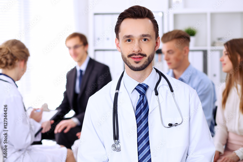 Friendly bearded male doctor with patients Friendly bearded male doctor with patients